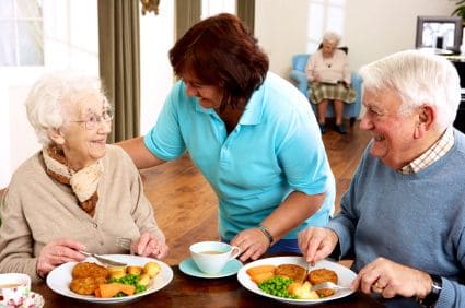 Caregiver encourages senior couple to eat